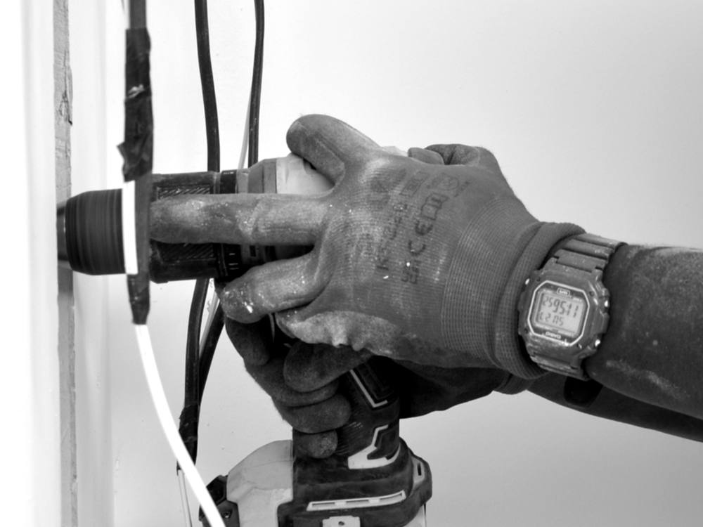 An electrician drilling and running cable through a wall
