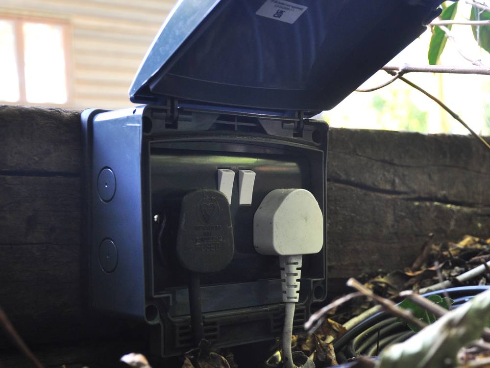 A weatherproof outdoor socket unit installed in a garden