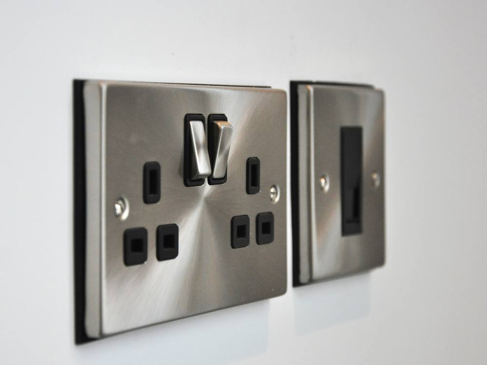 A brushed-steel double socket and switch neatly finished on a wall